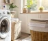 Interior of a bright French laundry room with a modern front-loading washing machine in use, soft natural light streaming through a window, folded